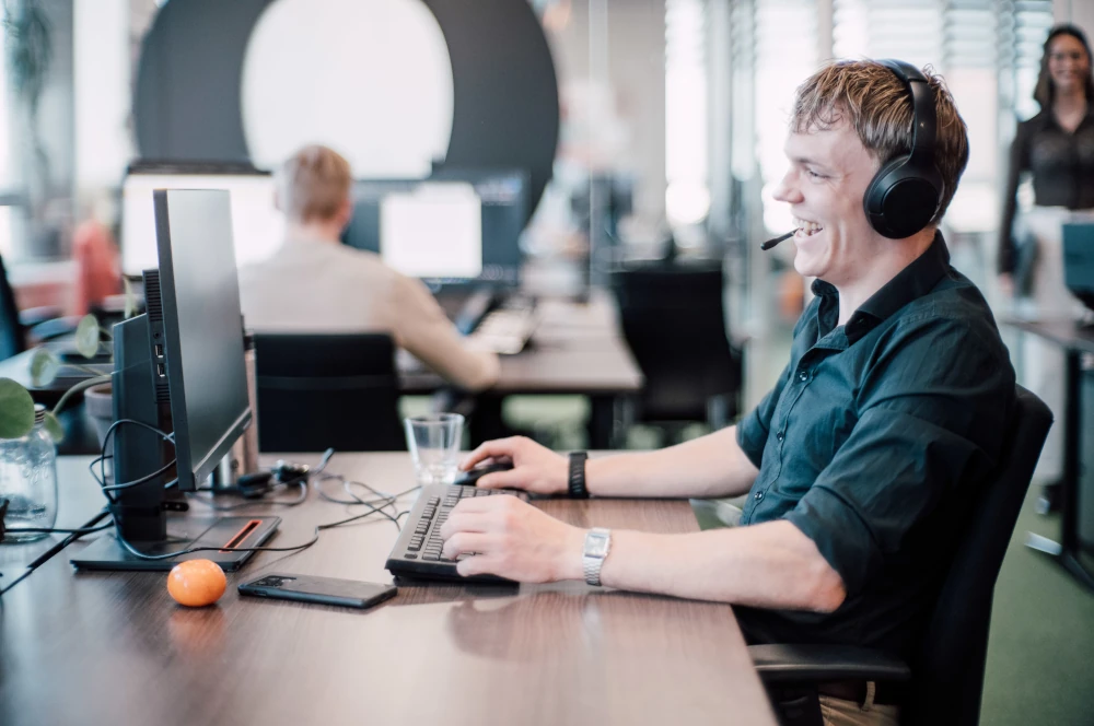 Meeting Expert met een headset op aan de telefoon zittend aan een bureau